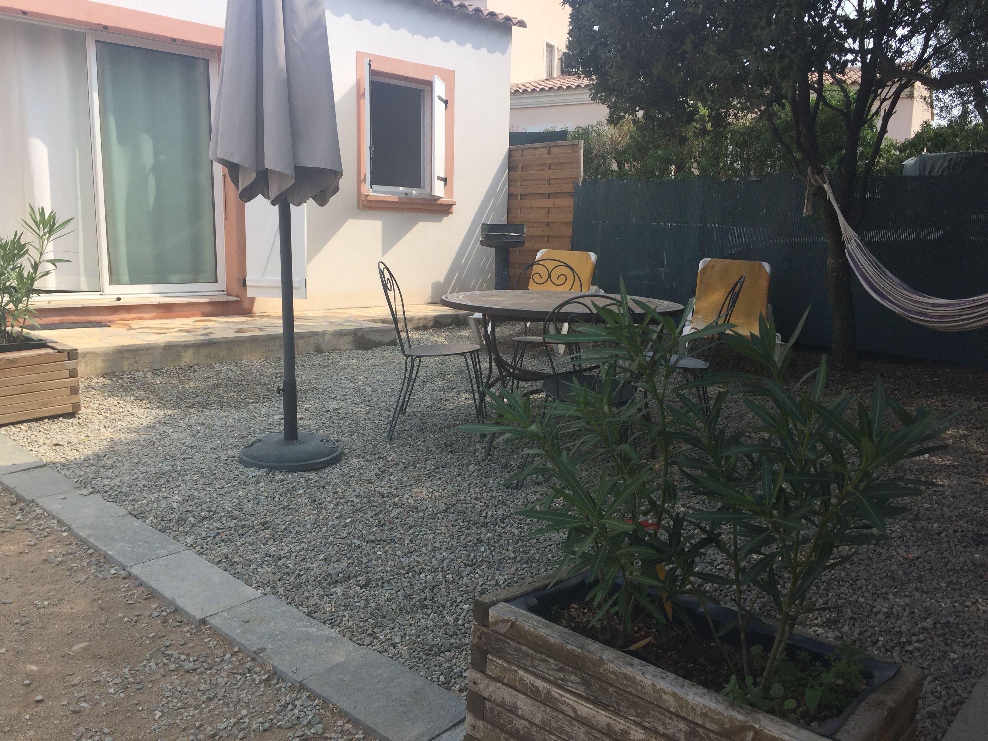 A patio area with a table and chairs, a hammock, and potted plants.