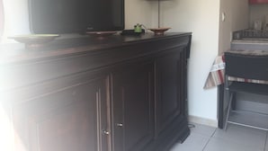 A dark wooden cabinet with a flat-screen TV, a lamp, and a small green object on top.