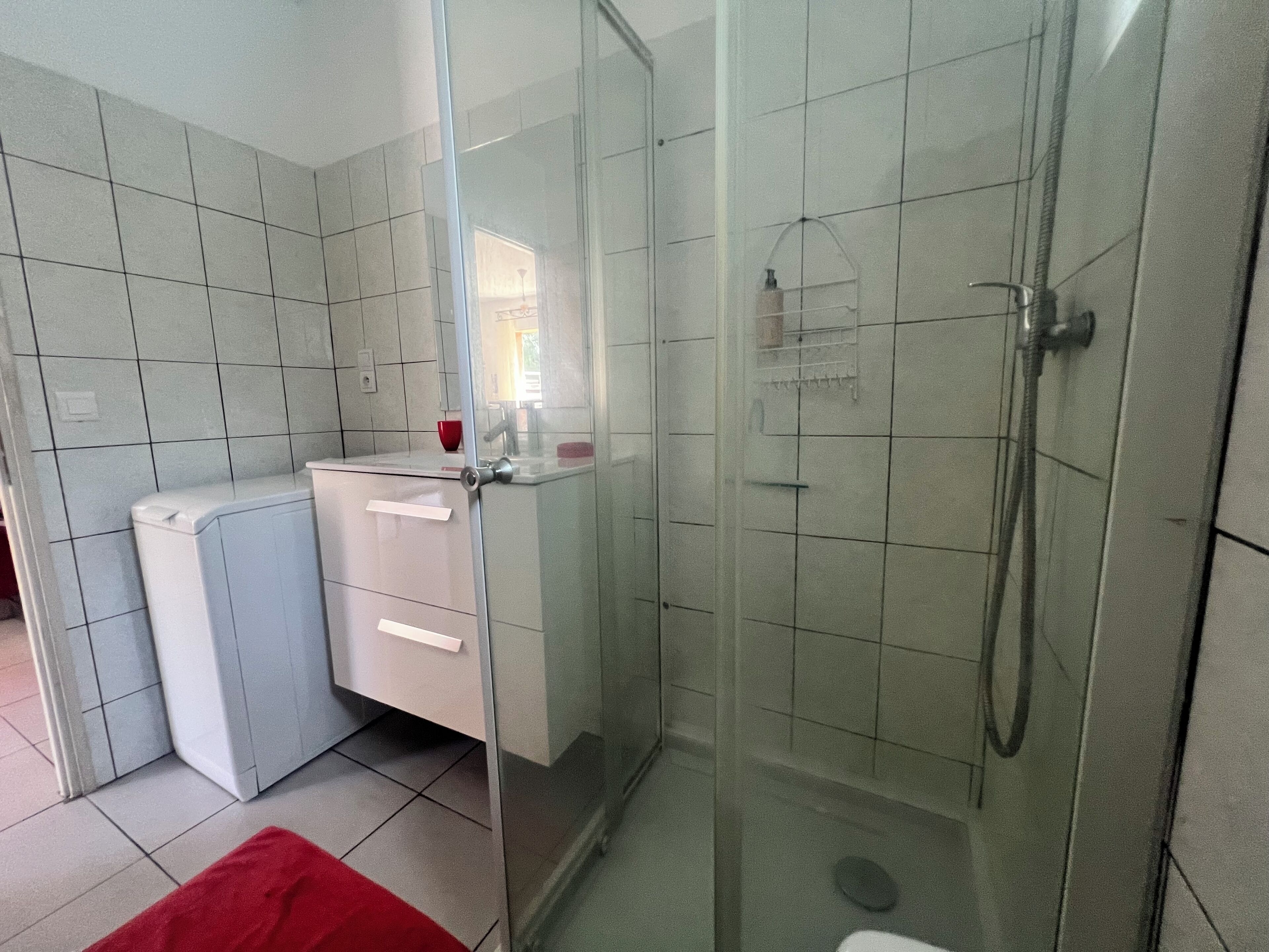 Een badkamer met een glazen douchecabine, een toilet en een wastafel.
