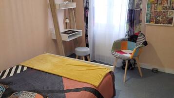 Una camera da letto con un letto, una scrivania, una sedia e una TV.