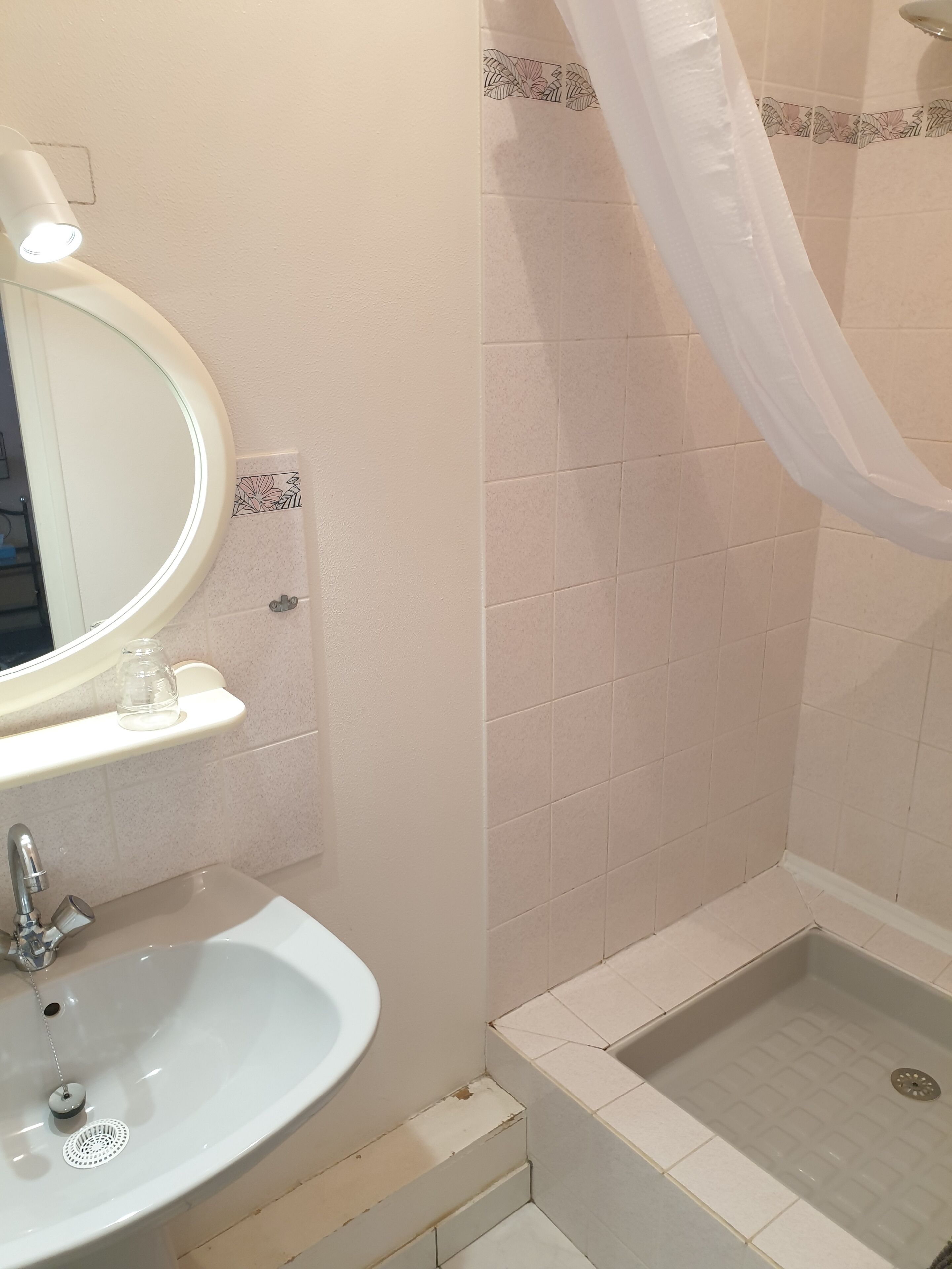 Ein Badezimmer mit Waschbecken, Spiegel, Dusche und einem weißen Duschvorhang.
