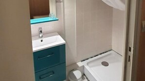 A bathroom with a shower, a sink, a mirror, and a toilet. - Le Relais du Château (Plaine-et-Vallées)
