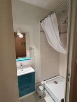 A bathroom with a shower, a sink, a mirror, and a toilet.
