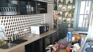 A modern kitchen with a central island, equipped with a toaster, bread, and various breakfast items. - Le Relais du Château (Plaine-et-Vallées)