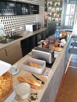 A modern kitchen with a central island, equipped with a toaster, bread, and various breakfast items.