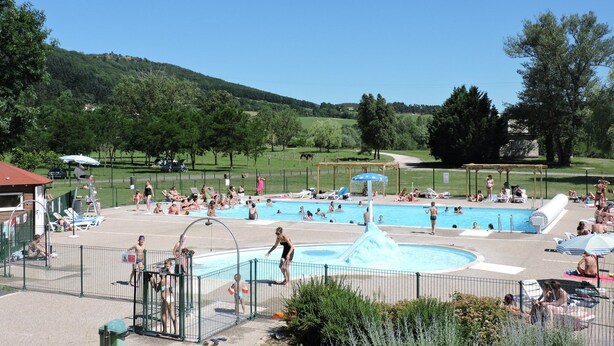 Piscina pública com várias pistas de natação, cercada por área com espreguiçadeiras e guarda-sóis.