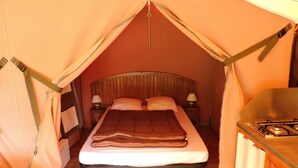 Quarto com tenda, uma cama, abajures e uma pequena cozinha.