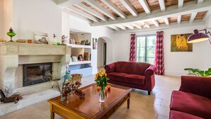 A living room with a fireplace, red sofas, a wooden coffee table, and a bookshelf. - Beautiful stone property with view and heated pool, 6 km from Gordes (Murs)