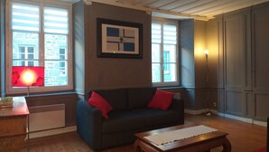 A living room with a dark blue sofa, red cushions, a wooden coffee table, and a framed picture on the wall.