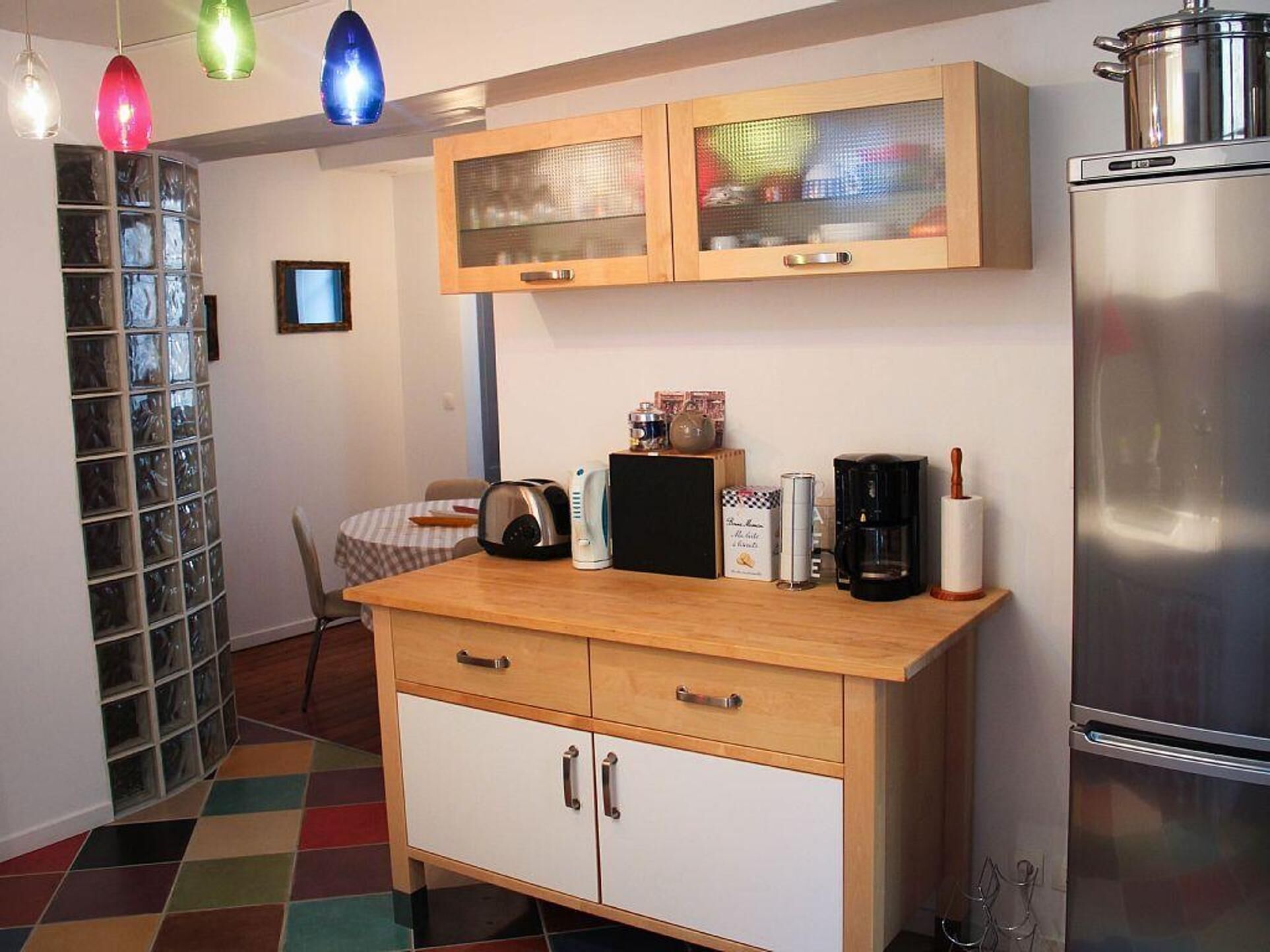 A compact kitchen with wooden cabinets, a stainless steel refrigerator, a coffee maker, and a toaster.