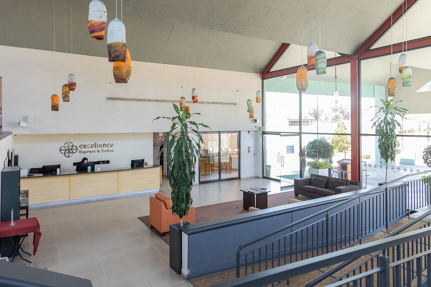 A reception area with a desk, chairs, hanging pendant lights, and a large window.