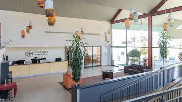 A reception area with a desk, chairs, hanging pendant lights, and a large window.