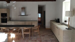 Een moderne keuken met houten kasten, een groot eiland en een eetgedeelte met stoelen.