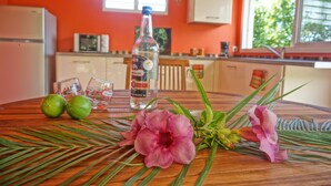 Una cocina con una mesa de madera, una botella de licor, dos vasos y una flor.