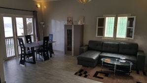 En stue med en grå sofa, et glasbord og et spiseområde med bord og stole.