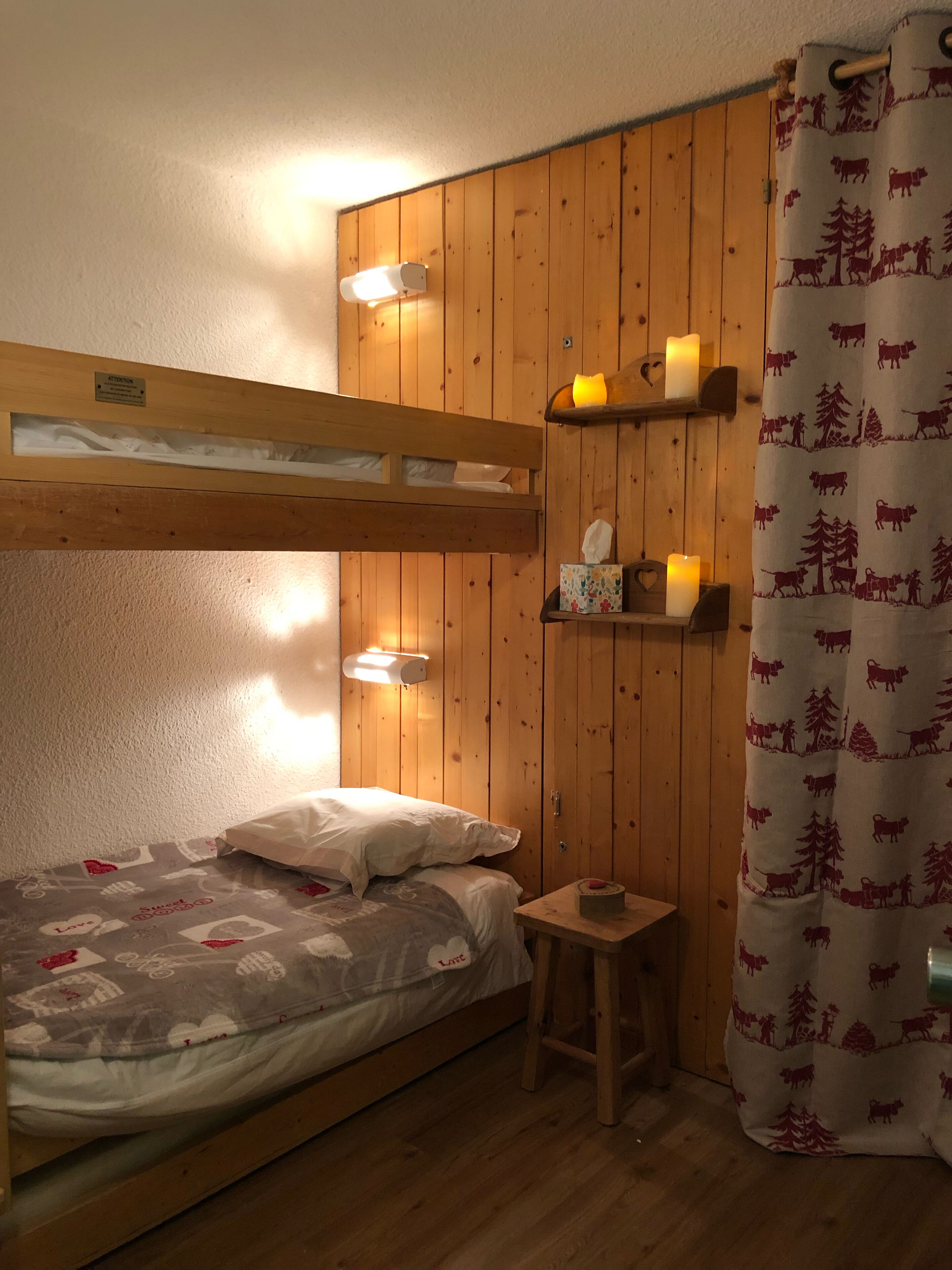 Ein gemütliches Zimmer mit einem Etagenbett, Holzwänden, einem kleinen Tisch und einer Nachttischlampe.