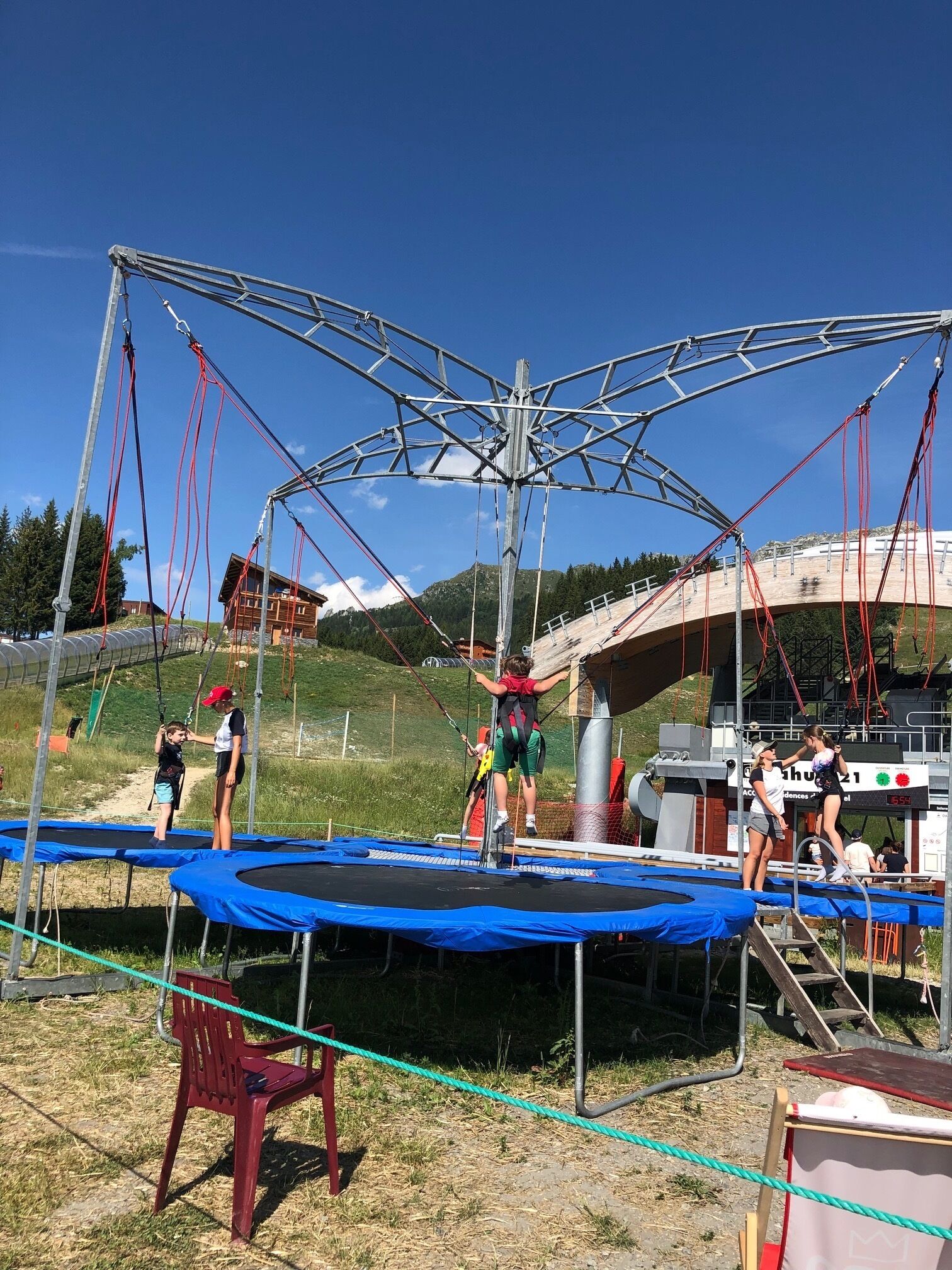 A trampoline with a metal frame structure, surrounded by a rope barrier.