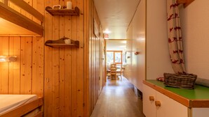 A wooden interior with a bed, shelves, and a table with a basket. - Apartment 4/5 PERS ARCS 1800 - WIFI (Arc 1800)