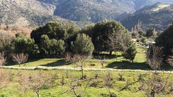 Un paysage montagneux avec un mur de pierre au premier plan et une vallée parsemée d’arbres et comprenant un petit village à l’arrière-plan.