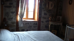 A bedroom with a bed, a window with curtains, a dresser, and a chair. - Country house 4pers (Montboudif)