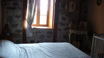 Une chambre à coucher avec un lit, une fenêtre avec des rideaux, une commode et une chaise.