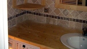 Une salle de bain avec un meuble-lavabo en bois, un évier et un pare-feu en carrelage.