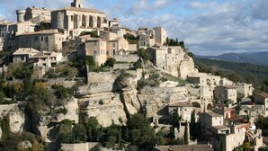Un poble històric construït en un turó, amb edificis de pedra i una torre destacada.