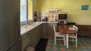 A compact kitchen with a refrigerator, sink, microwave, and a small dining table with chairs.