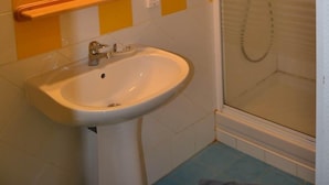 A bathroom with a white sink, a mirror, and a shower.