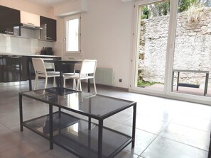 Una cucina moderna con zona pranzo, un tavolo in vetro e vista su un muro di pietra.