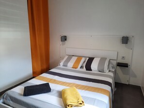 Una camera d'albergo con un letto, un comodino, una lampada e una tenda.