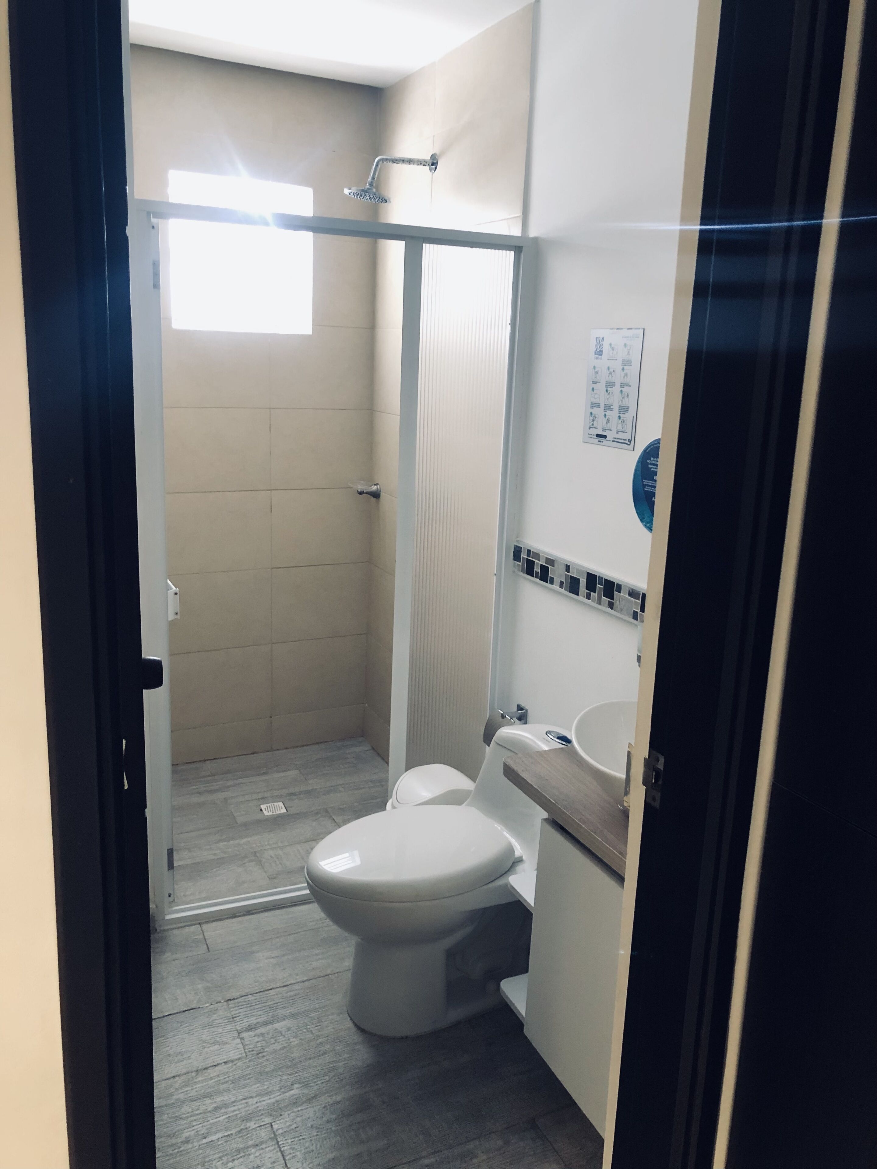 Un baño pequeño con inodoro, lavamanos y ducha.