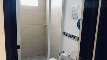 Un baño pequeño con inodoro, lavamanos y ducha.