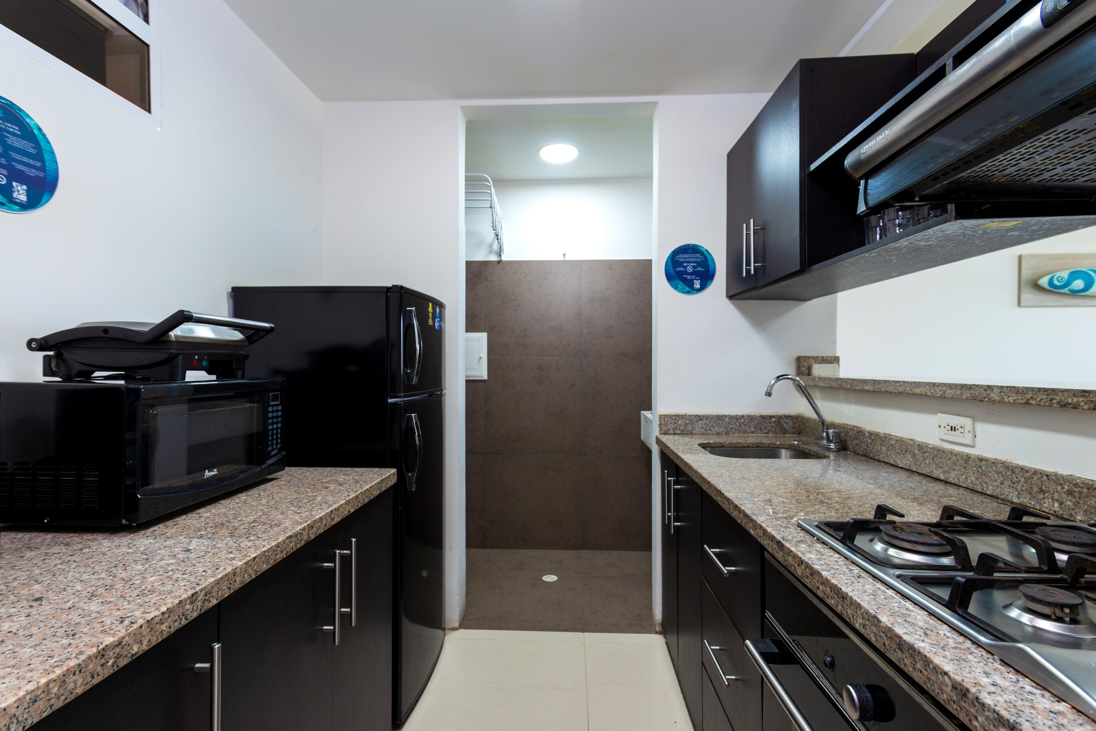 A compact kitchen with a microwave, refrigerator, and gas stove.