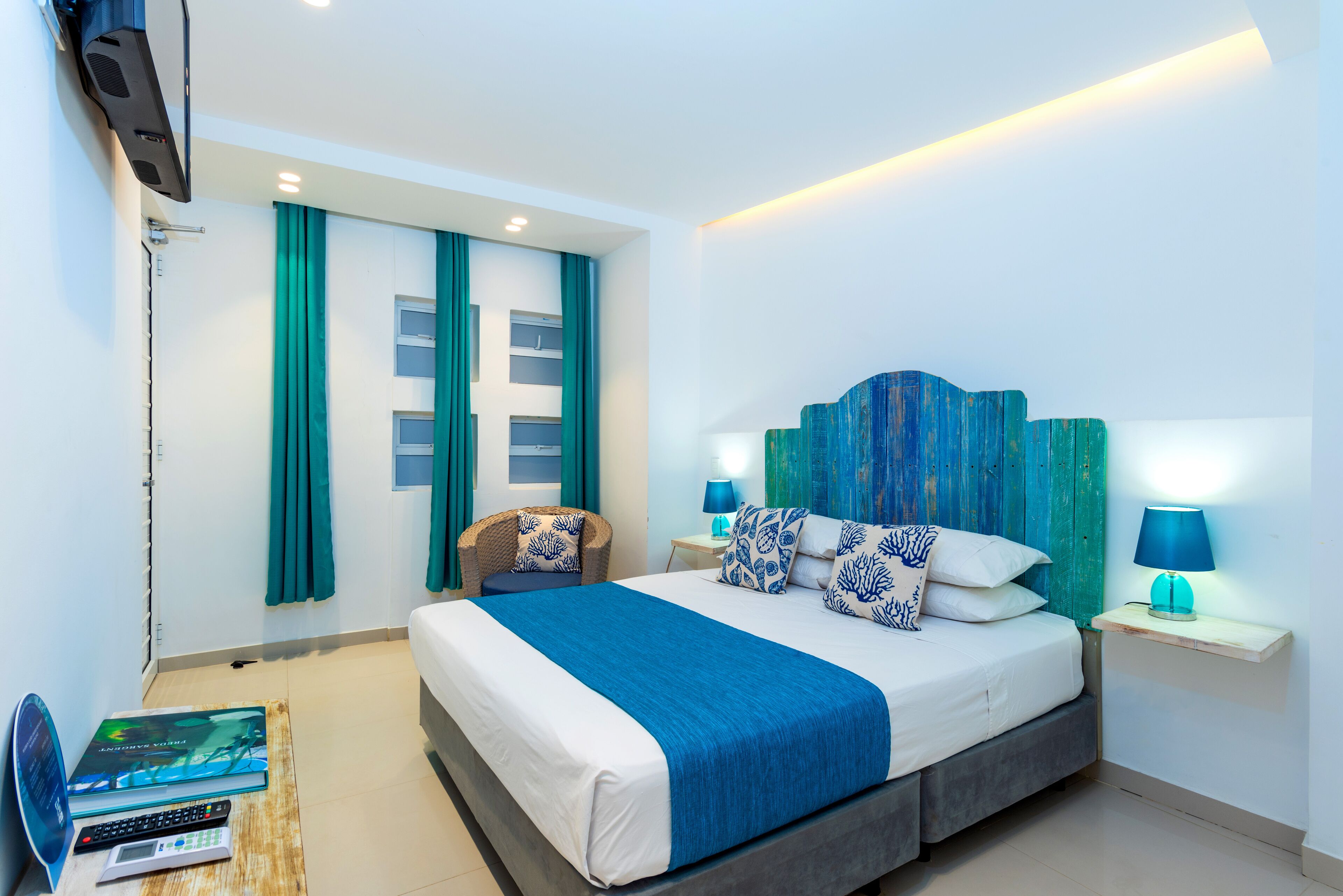 A modern hotel room with a large bed, two bedside lamps, a chair, and a TV mounted on the wall.