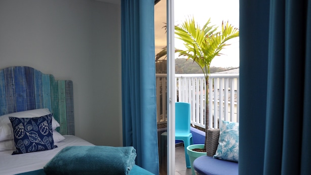 Une chambre à coucher avec un lit, une fenêtre et un balcon agrémenté d’une plante.