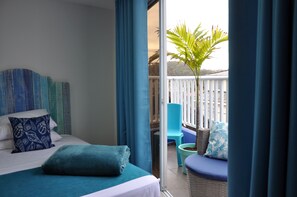 Un dormitorio con cama, ventana y balcón con una planta.
