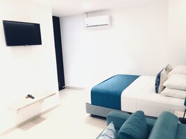 Una habitación de hotel moderna con una cama, un televisor y un equipo de aire acondicionado.