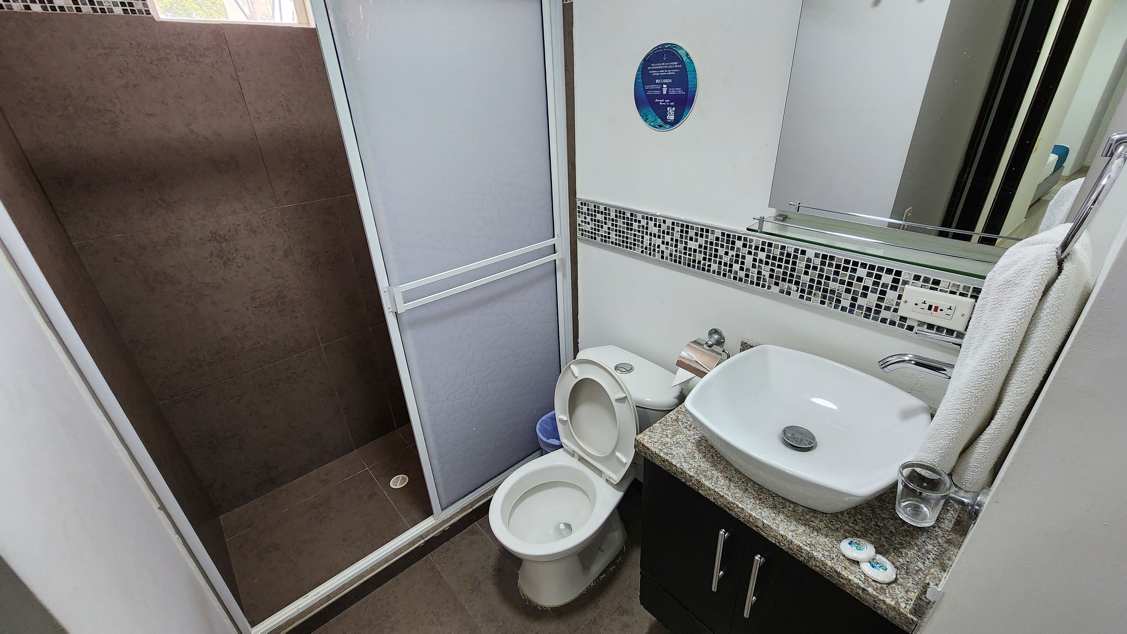 Une petite salle de bain comprenant une douche, des toilettes, un lavabo et un miroir.