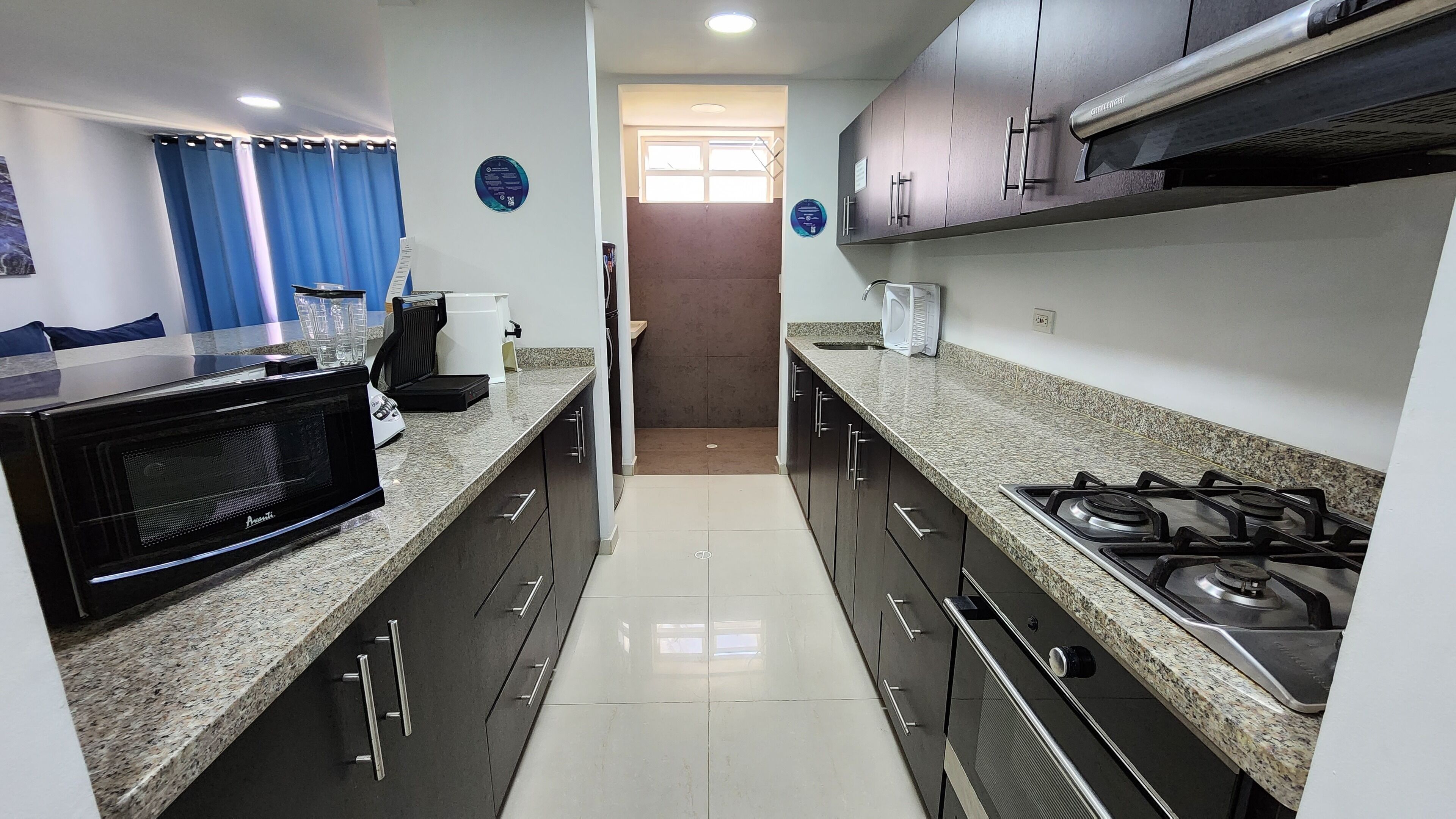 A modern kitchen with granite countertops, stainless steel appliances, and dark cabinetry.