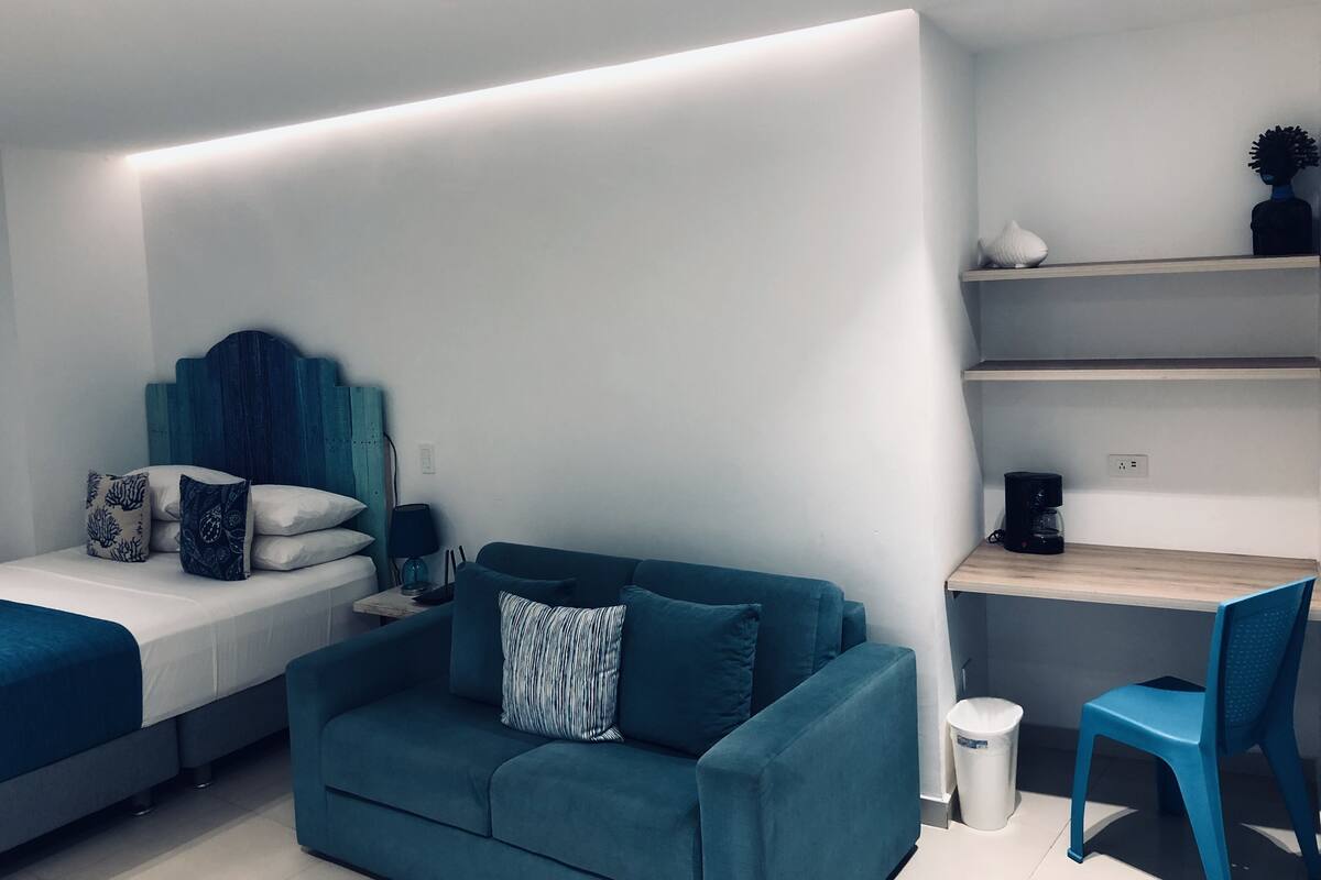 Una habitación moderna y funcional con cama, sofá, escritorio y silla.