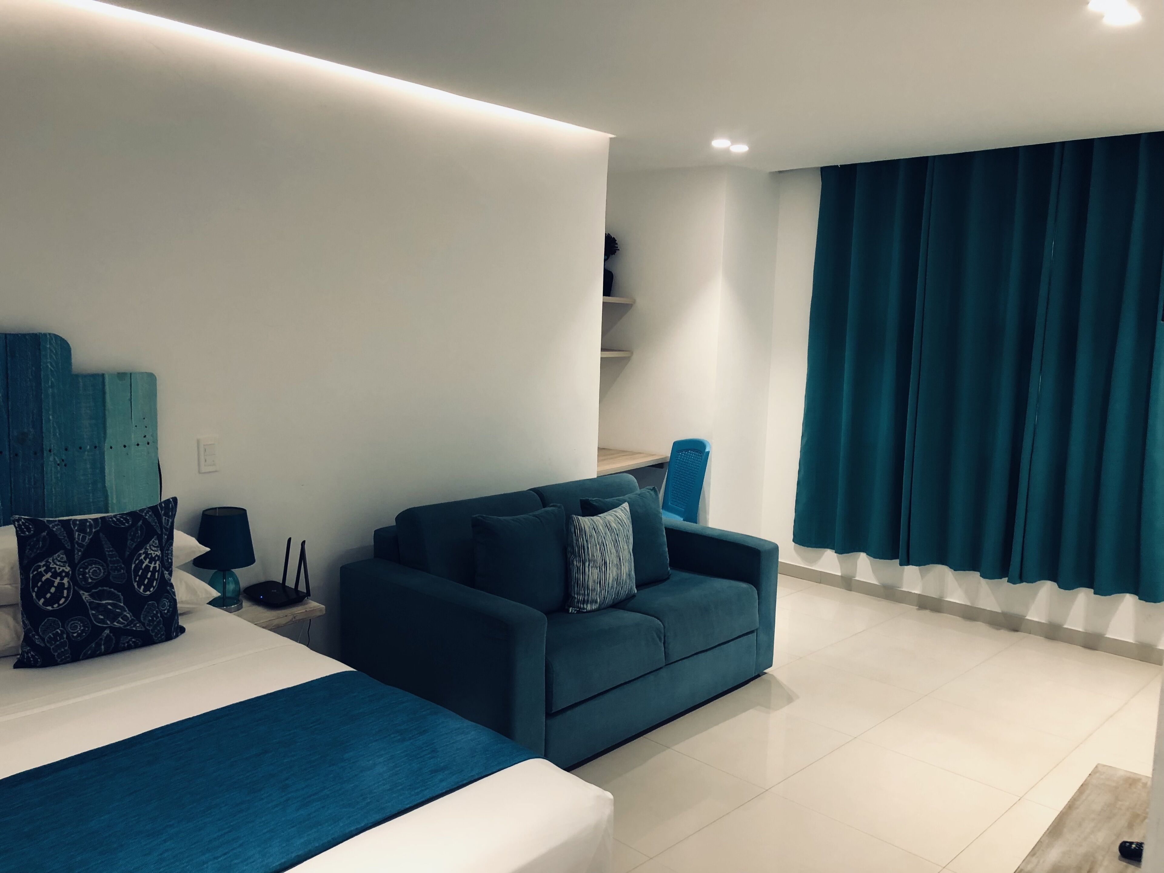 Ein modernes Schlafzimmer mit einem Bett, einem blauen Sofa und einem Schreibtisch.