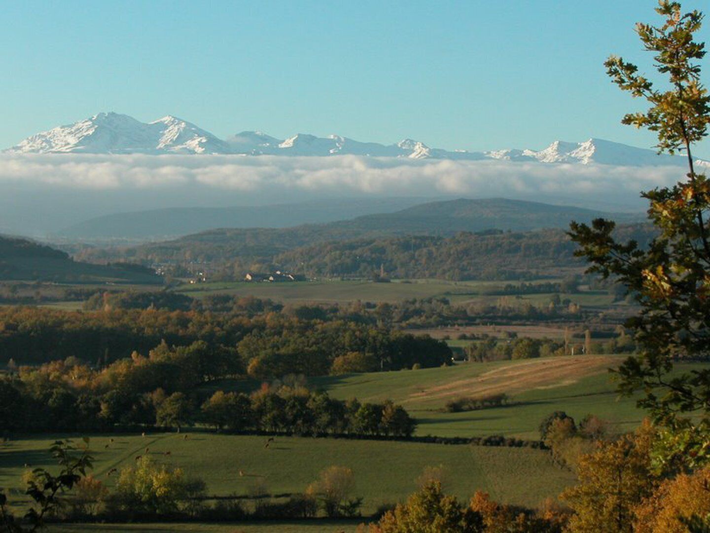 A panoramic view of a mountainous landscape with fields and scattered buildings.
