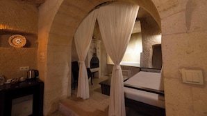 A room with a bed, a desk, a chair, and a fireplace. - Tafana Cave & Stone Lodge (Ürgüp)