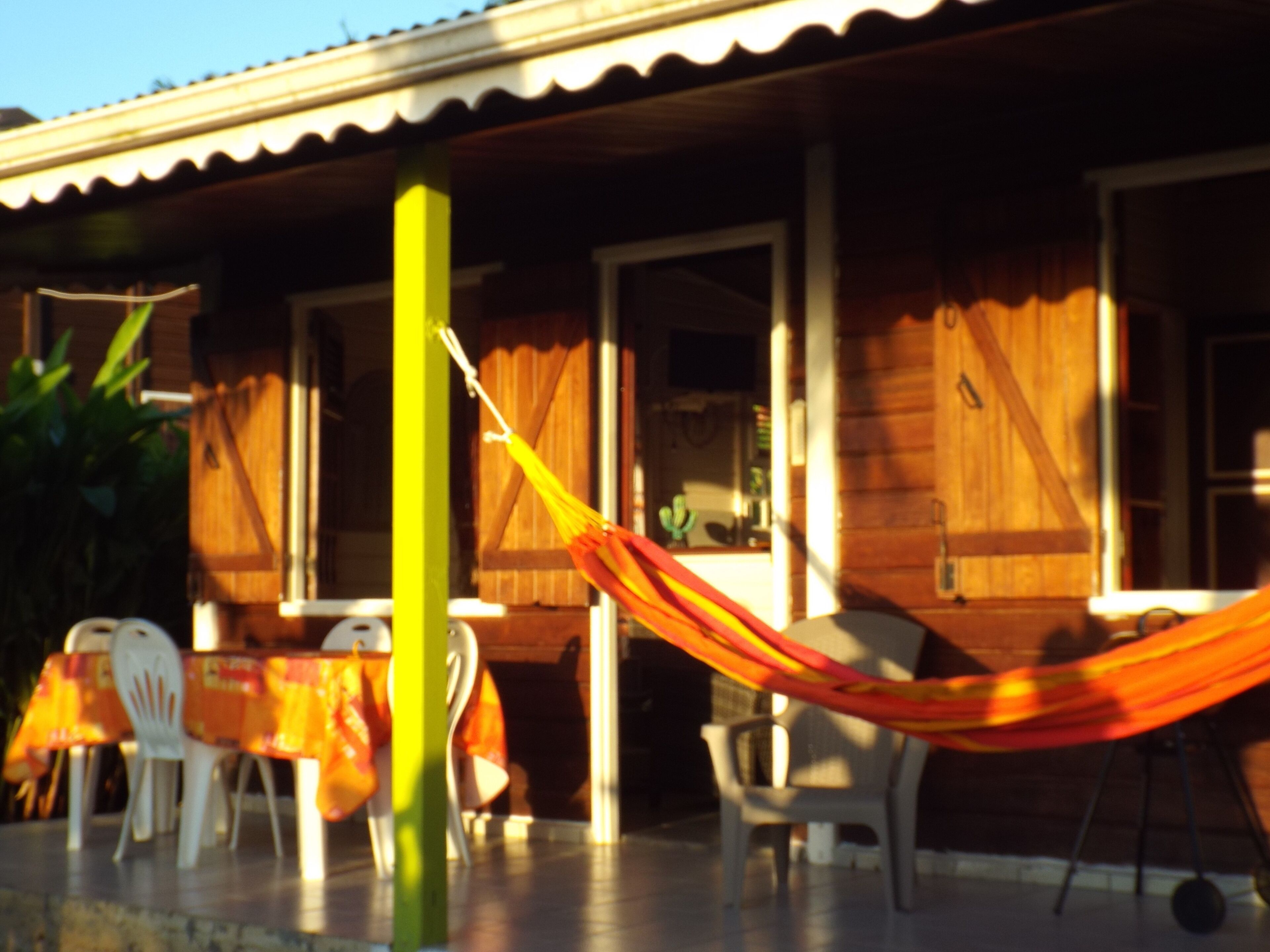 A wooden house with a porch, a hammock, and outdoor seating.