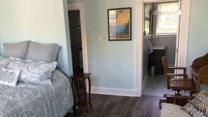 Ein Schlafzimmer mit einem Bett, einem kleinen Tisch, einem Sessel und einem Bild an der Wand.