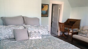 Ein Schlafzimmer mit einem großen Bett, einem hölzernen Stuhl und einem kleinen Tisch.