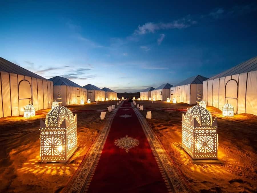 A row of tents with a central walkway, each tent featuring a patterned lantern at the entrance.