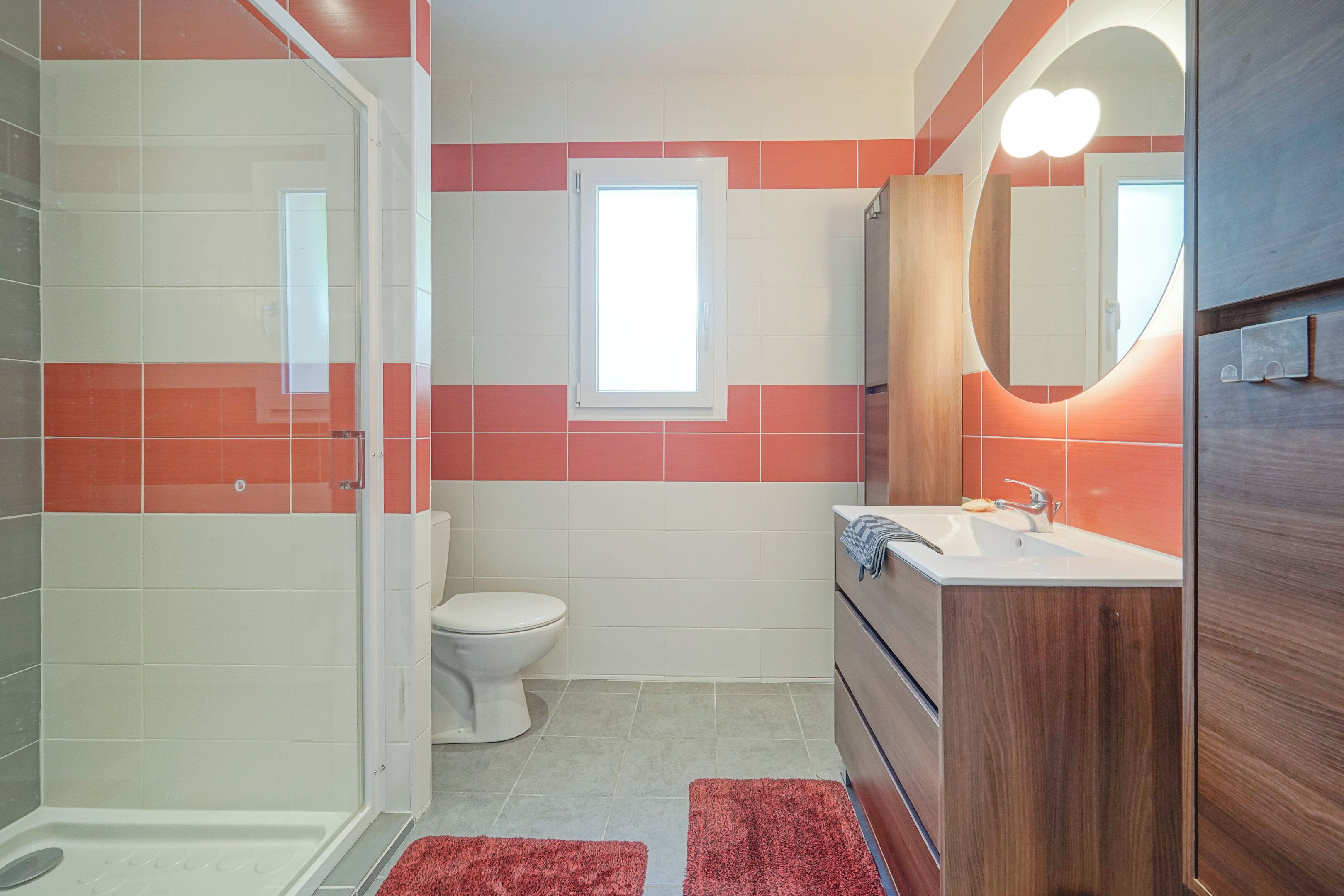 Une salle de bain équipée d’une douche, de toilettes, d’un lavabo et d’un meuble-lavabo en bois.