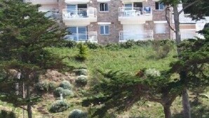 Un immeuble à plusieurs étages, doté de balcons, avec une plage en premier plan.